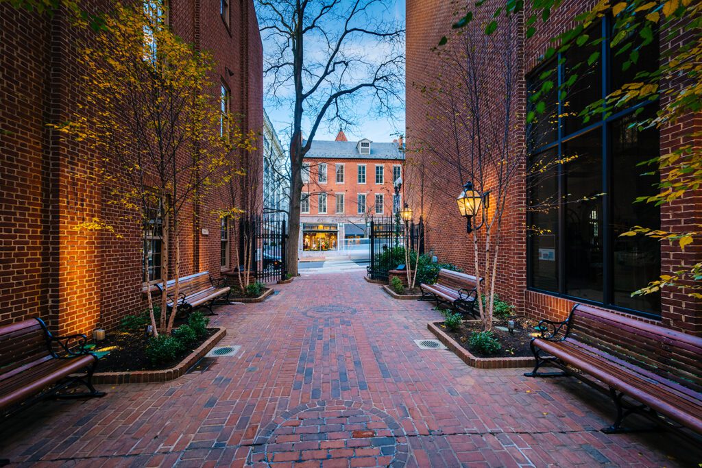 a brick walkway between two buildings with benches