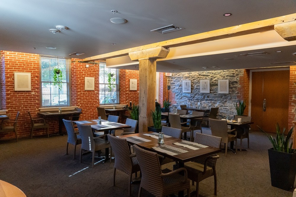 a restaurant with tables and chairs in front of a brick wall