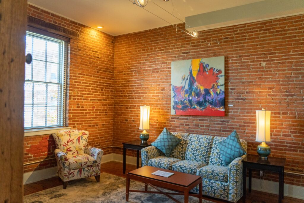 a living room filled with furniture next to a brick wall