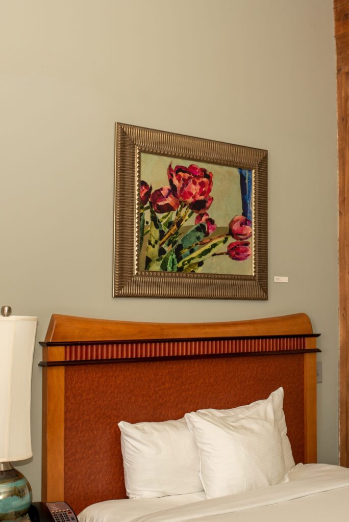 a bed with white pillows and a painting on the wall