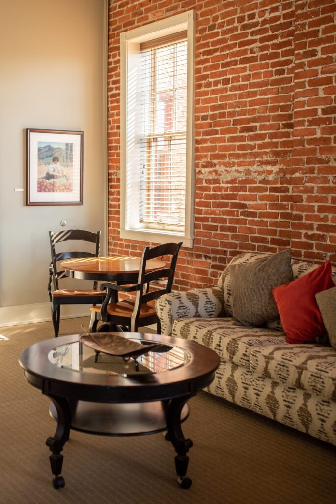a living room filled with furniture and a brick wall