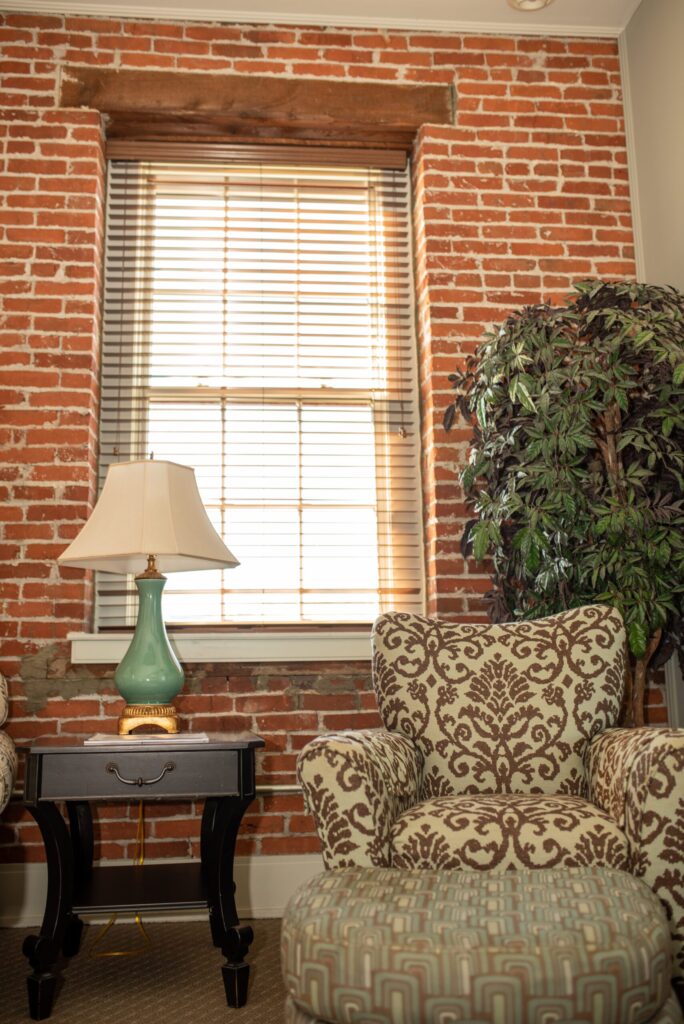 a living room with a chair, lamp and brick wall