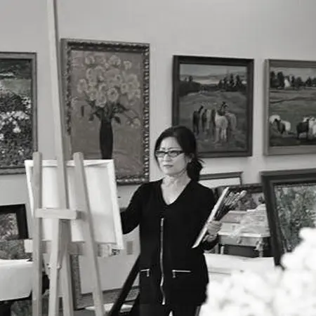 a woman standing next to a easel in front of paintings