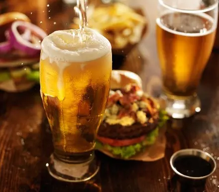 a glass of beer is being poured into a burger